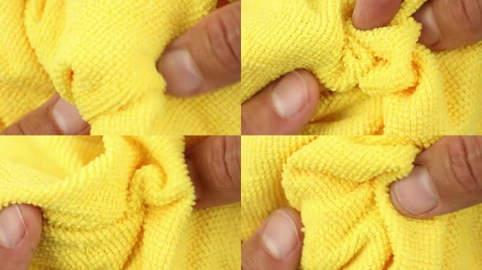 手测试和拉伸黄色超细纤维除尘布，吸水合成织物质地的特写视图