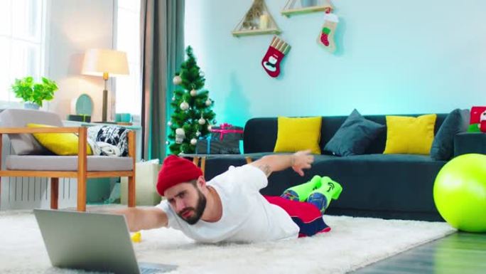 在家锻炼在客厅的地板上的家伙做一些锻炼，以伸展背部，他看着如何通过笔记本电脑做。在阿里·阿列克谢拍摄