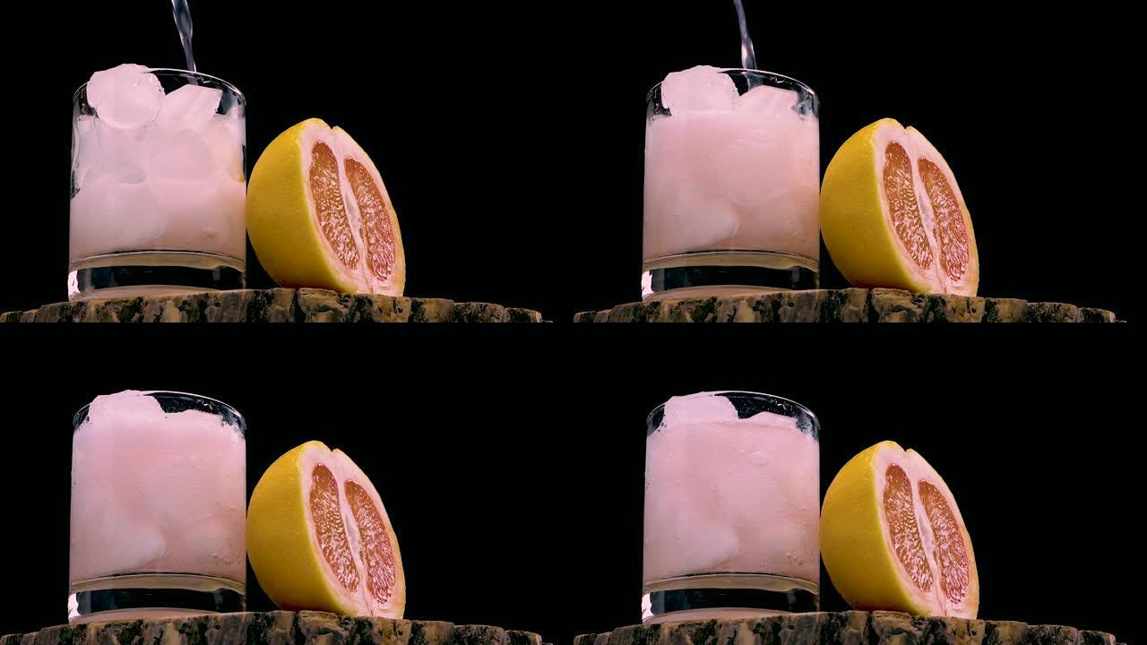 将葡萄柚汁倒在黑色背景的木制桌子上。将冰镇鸡尾酒倒入带有葡萄柚片的玻璃杯中。天然果汁。夏季冰镇饮料