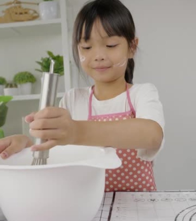 快乐的亚洲孩子在家里学习做饼干，女孩在搅拌碗里搅拌面粉。