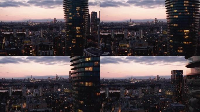 向前飞去竞技场塔高大的现代圆柱形公寓楼。暮色天空下的城市景观。英国伦敦