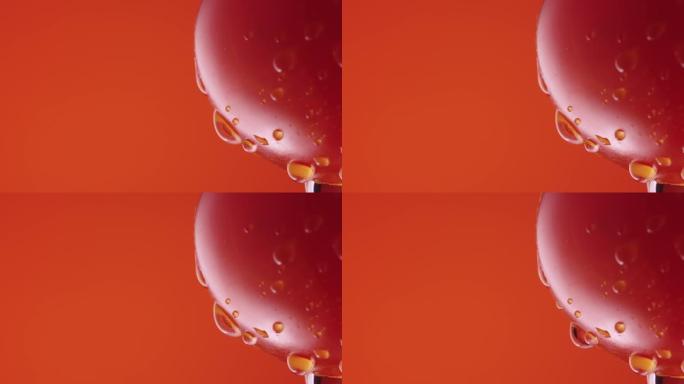红色工作室背景上水滴成熟的番茄。红色番茄表面滴下水滴的宏观镜头。屏保和壁纸的湿蔬菜。慢动作。特写