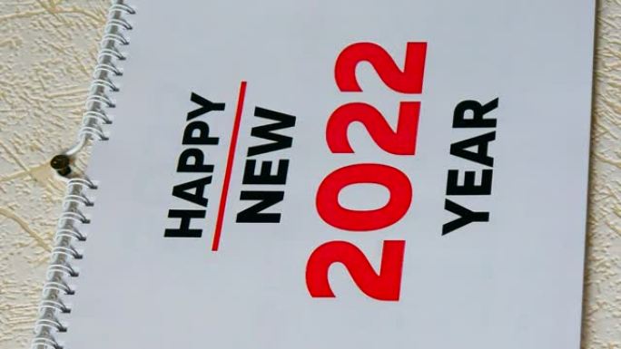 一个男人的手的特写镜头撕下墙上2021日历的12月页，然后是新2022日历的标题和1月页。垂直视频