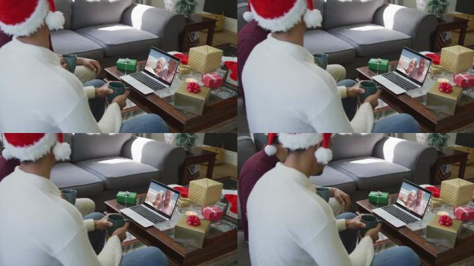 混血儿父子使用笔记本电脑与屏幕上的幸福夫妇进行圣诞节视频通话