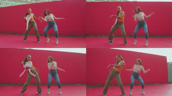 两个年轻的舞女酷动人，展示现代舞的乐趣。女舞者在红墙外表演