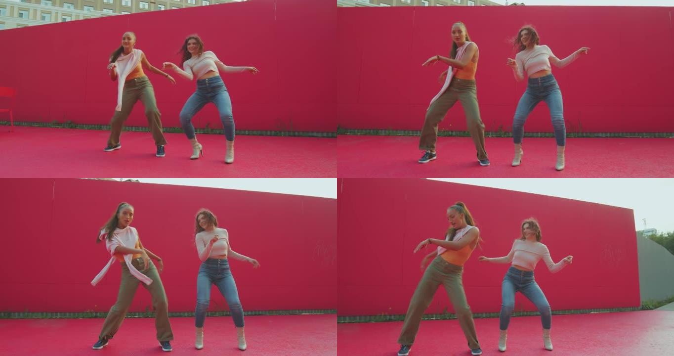 两个年轻的舞女酷动人，展示现代舞的乐趣。女舞者在红墙外表演