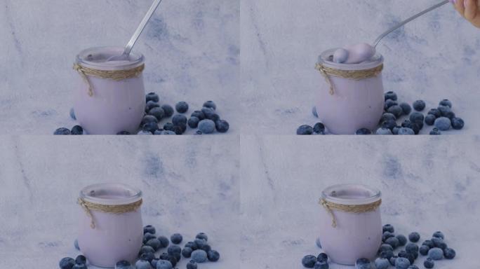 桌上放着酸奶和蓝莓的碗。女人吃蓝莓酸奶和新鲜蓝莓。健康早餐。超级食品健康饮食素食素食