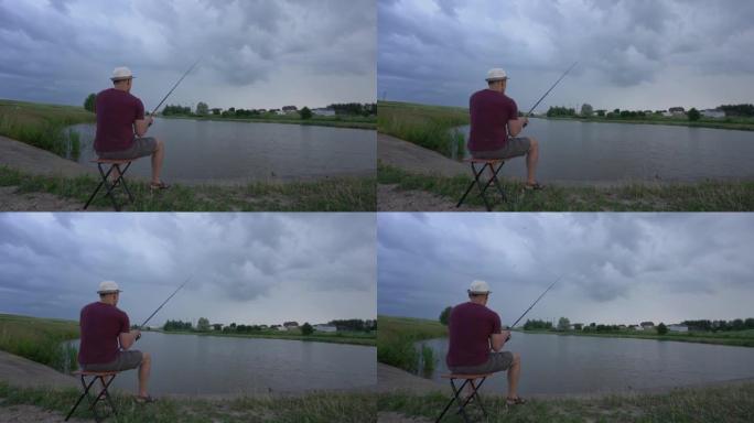 男子钓鱼坐在池塘岸上的椅子上，从后面看