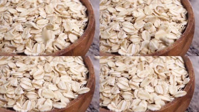 未煮熟的干燕麦片以慢动作掉入木桌上的乡村木碗中