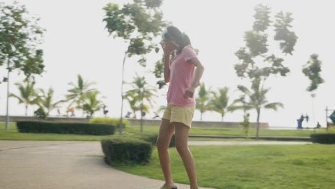亚洲女孩在公园户外玩冲浪滑板，早晨，白天，生活方式的概念。