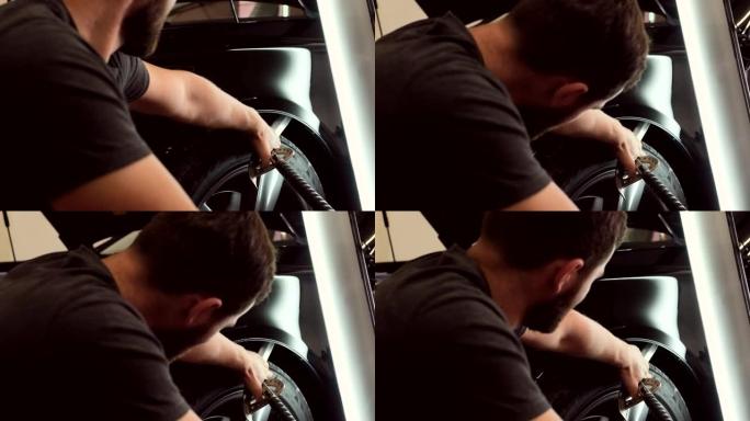 汽车服务技术人员在车轮上进行黑色车辆的无漆凹痕去除过程。
