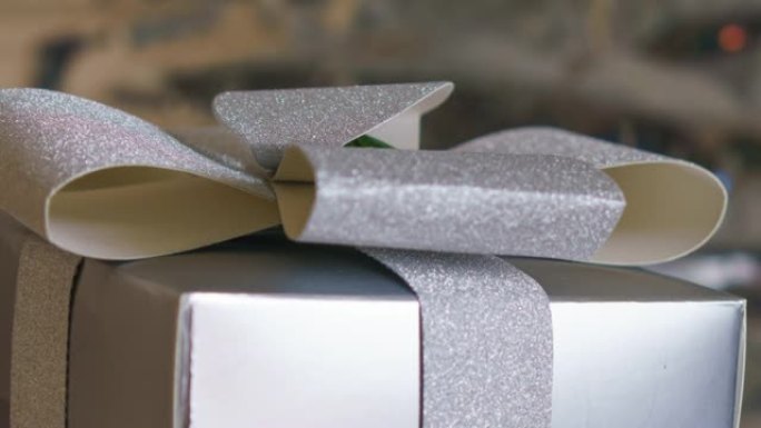 一个漂亮的礼品盒，银色蝴蝶结在闪闪发光的银色背景上。