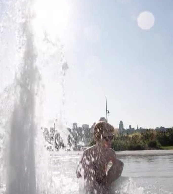 可爱的红发男孩在喷泉里玩耍
