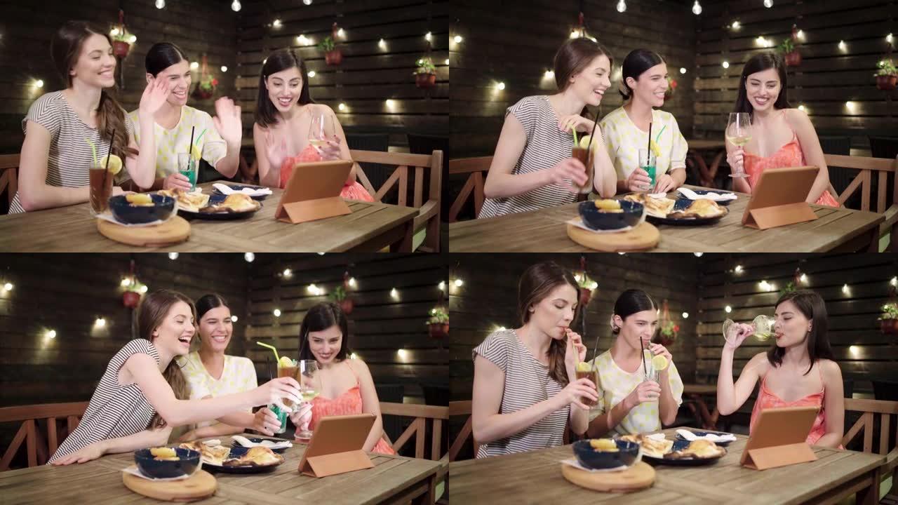 开朗的高加索女性朋友，在餐厅的社交聚会中享受鸡尾酒，同时与国外朋友进行视频通话