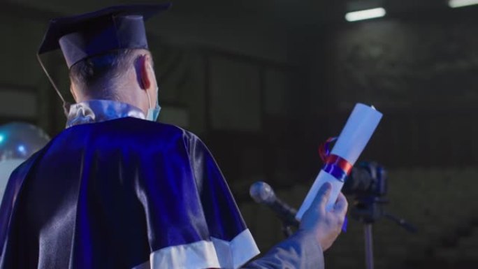 在线大学毕业，学术论文男讲师r，戴着医用口罩的帽子通过会议室的视频链接向麦克风附近的毕业生颁发文凭