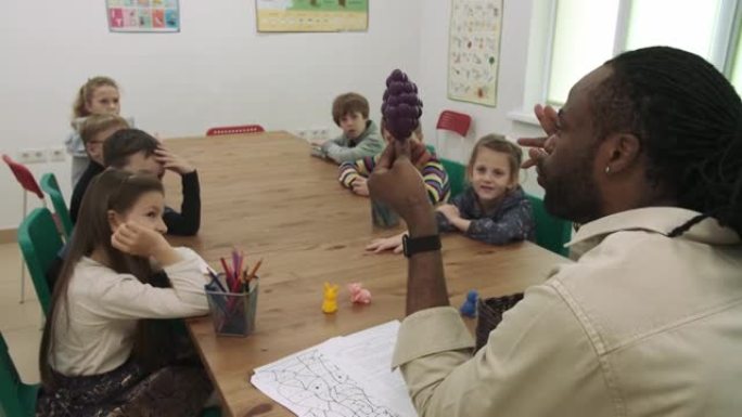 非裔美国老师向一群孩子教授水果和动物
