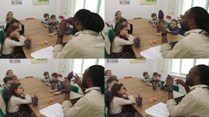 非裔美国老师向一群孩子教授水果和动物