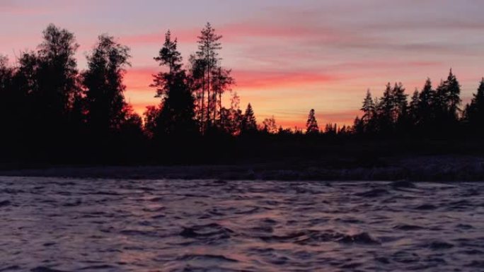 河边的夜景，岩石海岸的树木轮廓，日落色的天空背景