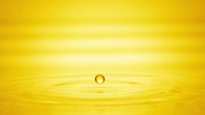黄色液体滴落在液体表面上，形成圆圈
