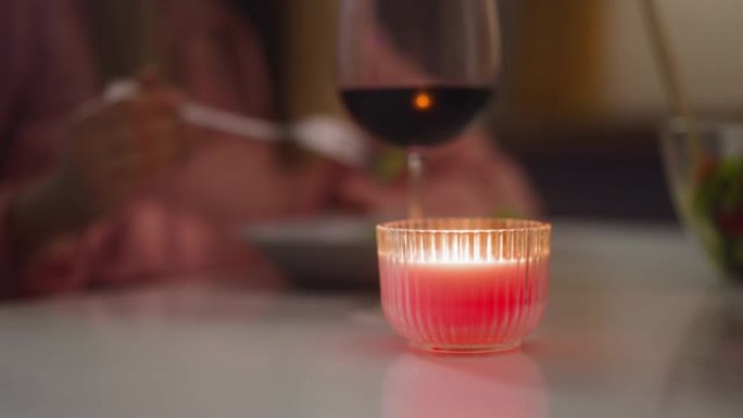 人们吃晚饭时，烛台上的蜡烛在桌子上燃烧