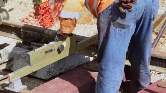 木枕铁路轨道的施工。用钻头的工人使固定在轨枕上的导轨的螺栓固定在孔中。