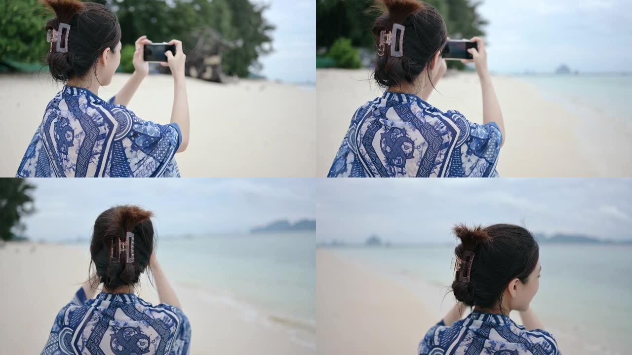 移动视频年轻的泰国/中国亚洲女性使用社交媒体内容在白色沙滩上行走上传故事周末在泰国南部甲米的海滩海岸