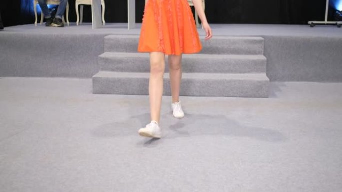 女模特穿着白色运动鞋走在t台讲台上。女鞋。