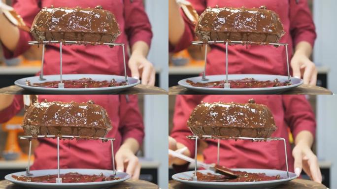 糕点厨师的女性手用硅胶烹饪刮刀将巧克力糖霜和坚果涂在棕色蛋糕上。用左手旋转蛋糕