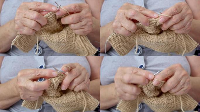 编织的特写镜头，一位祖母为她的孙子编织温暖的羊毛袜子过冬。布满皱纹的老手用织针编织。针线活是退休人员