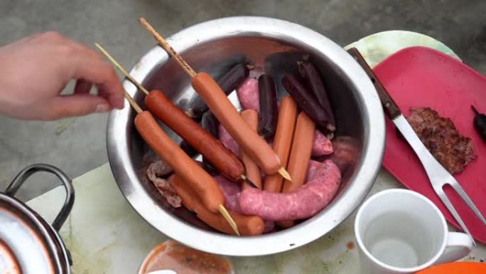 一个装有热狗香肠的碗的特写镜头，木棍，血香肠和香肠在4k白天带到屋顶烤架上