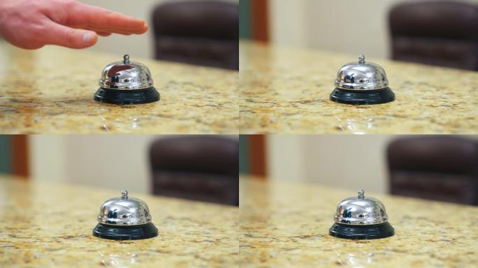 酒店的金属铃铛按钮。用手触摸桌子上的电子铃，打电话给酒店的接待员。特写。