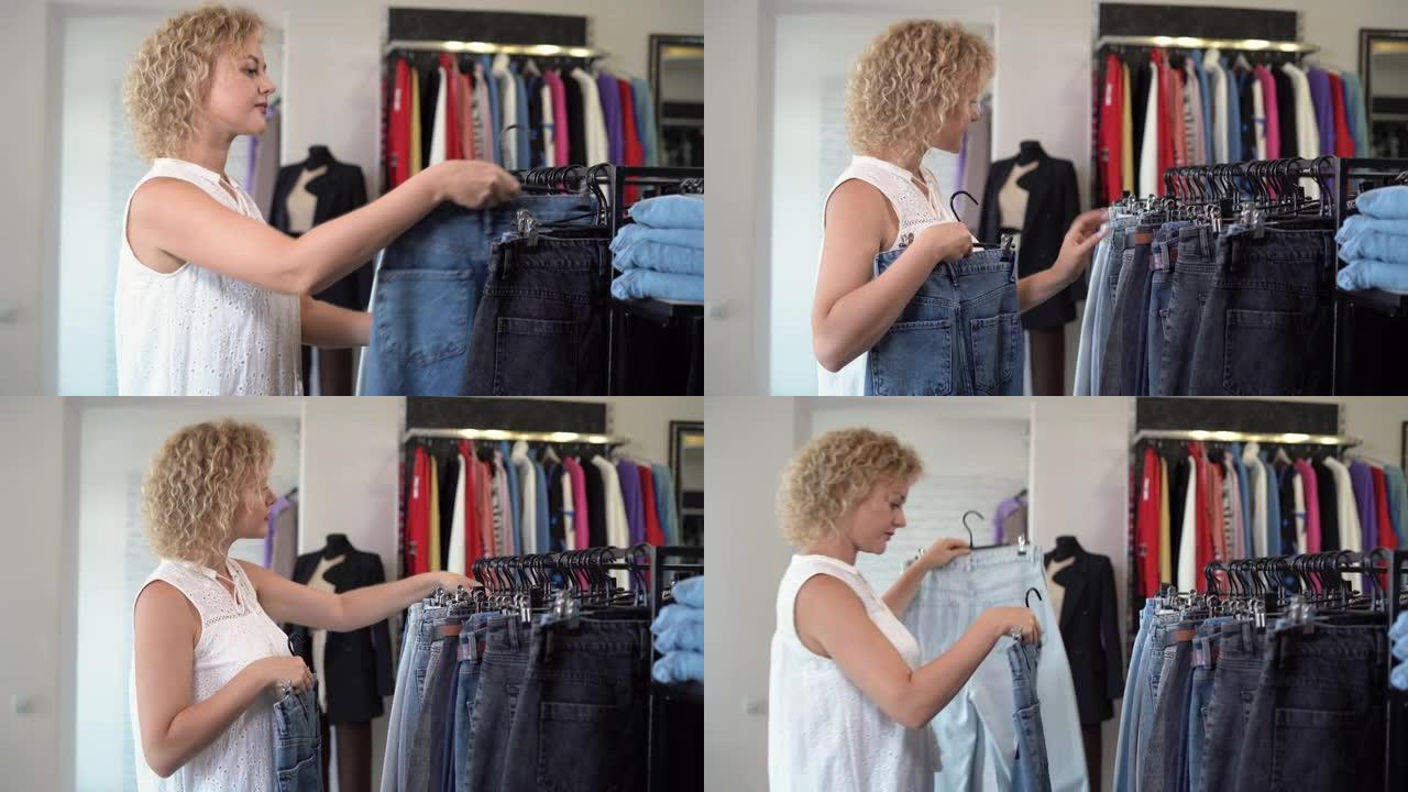 一位年轻女士站在一家服装店里，从窗户里挑出两条牛仔裤子，然后去试衣间。
