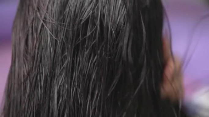一名中年亚洲妇女在家中用吹风机吹干头发