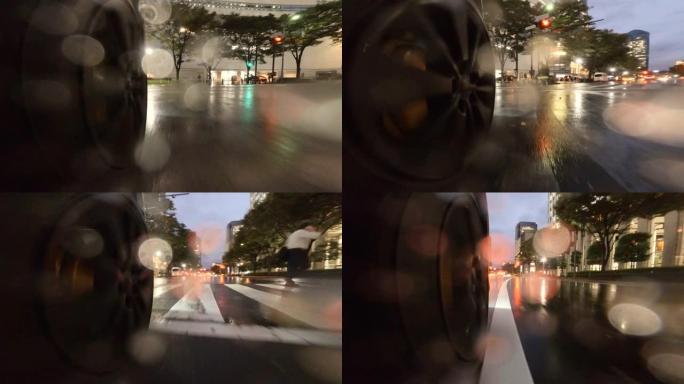 在雨夜开车穿过城市。汽车车轮的特写。在人们正在穿越的十字路口右转