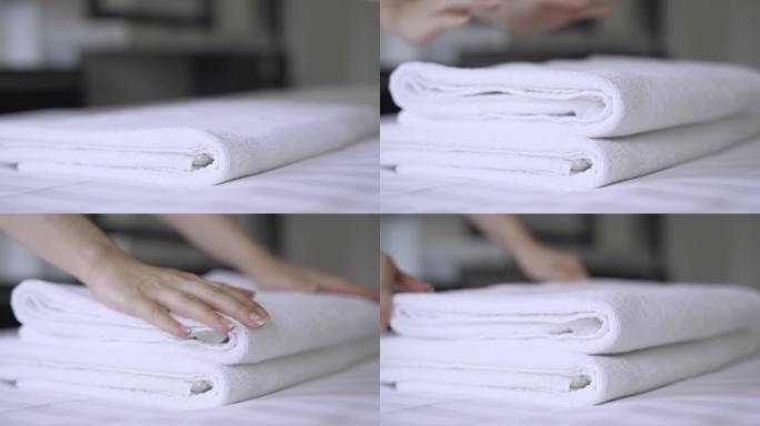 特写手在床上放一叠新的干净浴巾