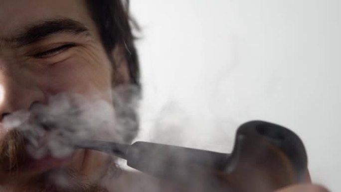 男人正在抽烟斗，从鼻孔中呼出大量烟雾，皱着眉头