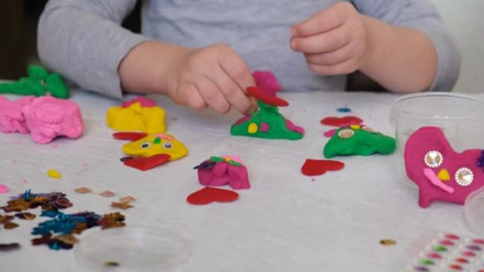 小女孩的手用五颜六色的粘土面团、橡皮泥、家庭教育游戏制作花和太阳等。早期发展理念。带孩子的教育和娱乐