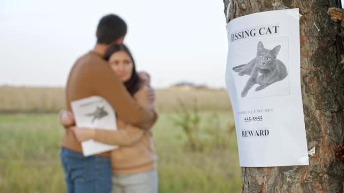 心烦意乱的夫妇在公园拥抱，专注于失踪猫的海报