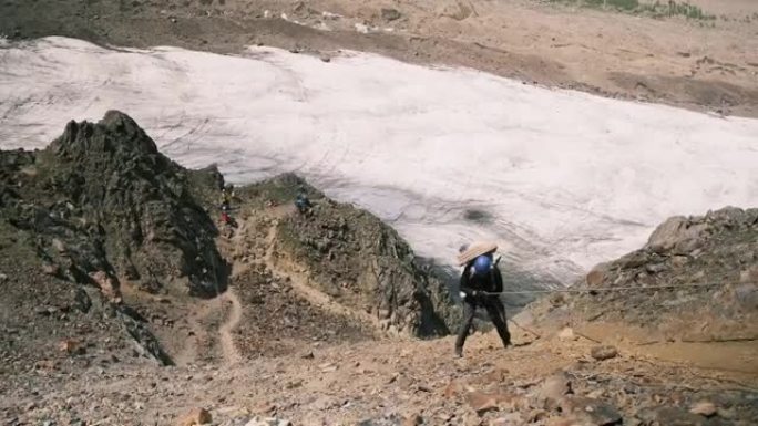 一个人带着绳子下山，一群游客在下面等着他