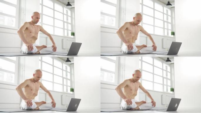 秃头的高加索赤膊瑜伽士在笔记本电脑相机上展示锻炼