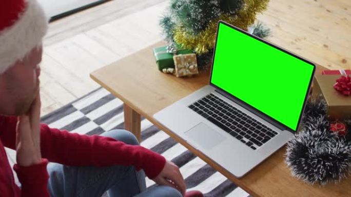 戴着圣诞老人帽子的白人男子进行笔记本电脑圣诞节视频通话，带有绿屏复制空间