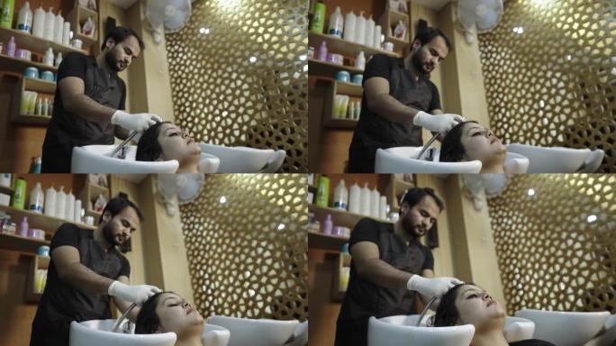 一名男性水疗中心工作人员正在一家现代沙龙为女性客户洗头