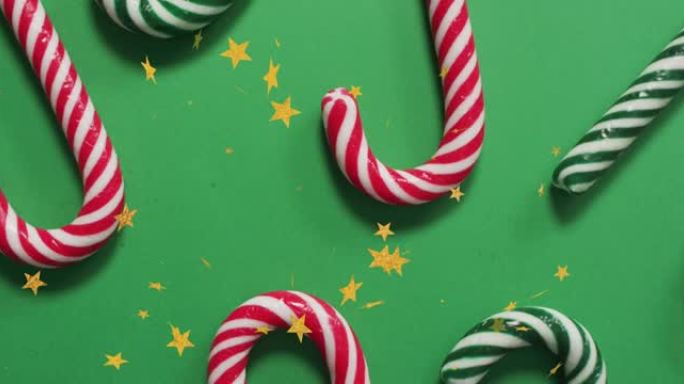 绿色背景上的圣诞节星星掉落在圣诞节糖果上的动画