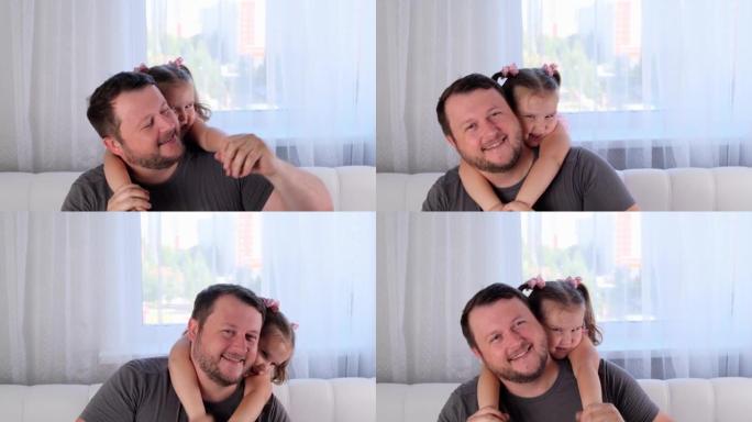 3岁的笑小女儿和父亲轻轻拥抱，在家里玩得开心。和你的孩子玩得开心，傻瓜概念。父亲节。育儿，孩子和父母