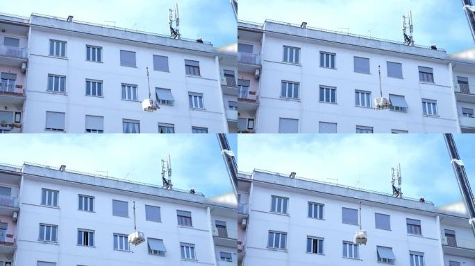 建筑起重机在住宅建筑屋顶顶部提升信号发射器设备，用于安装先进的5g塔架天线，以实现更好的信号通信。团