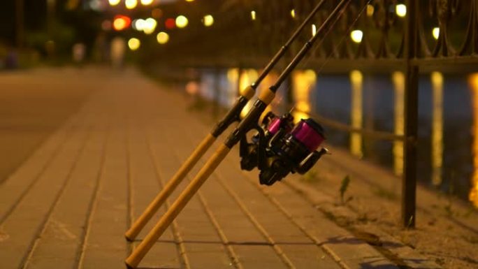 两根带有红线的鱼竿在傍晚时靠在城市的围栏上。