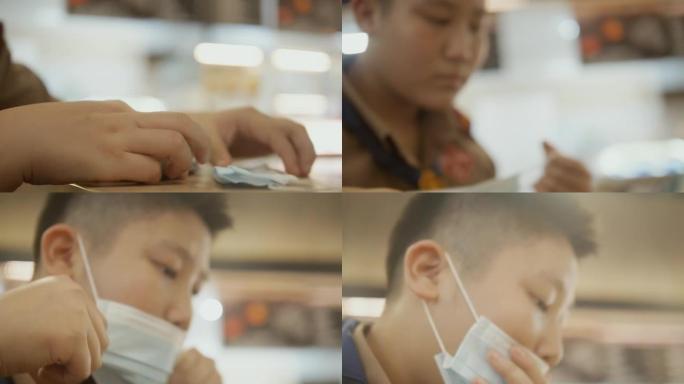 亚洲男生戴着口罩，在美食广场玩手机游戏，社交疏远生活理念。