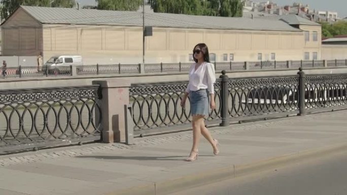 迷人的年轻女士走在城市街道上。穿着牛仔裙的漂亮女人在城市散步，享受阳光明媚的日子。拥有时尚的服装和迷