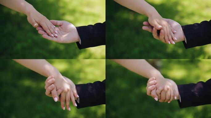 恋人互相拉手，轻轻地握住手。特写拍摄。大自然中的镜头