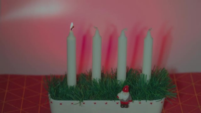 近景的人点燃第一支蜡烛在传统的烛台上第一次出现在一个红色的背景。 瑞典。
